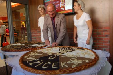 Ředitel Vladimír Dubják krájí obří koláč. 