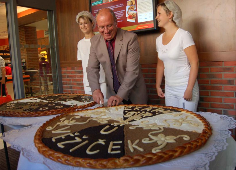 Ředitel Vladimír Dubják krájí obří koláč. 