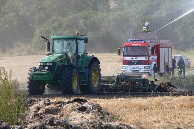 Hasiči a velký zemědělský stroj při likvidaci požáru pole u Traplic.
