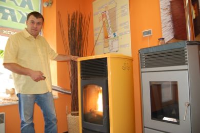 Petr  Mikulík reguluje dálkovým ovladačem hoření v kamnech, která spalují peletky. 