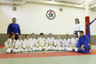 Anna Polesová Skládalová (vlevo v modrém kimonu) se svými svěřenci.  Vpravo stojí její dcera Kateřina Rejdíková, také trenérka juda.