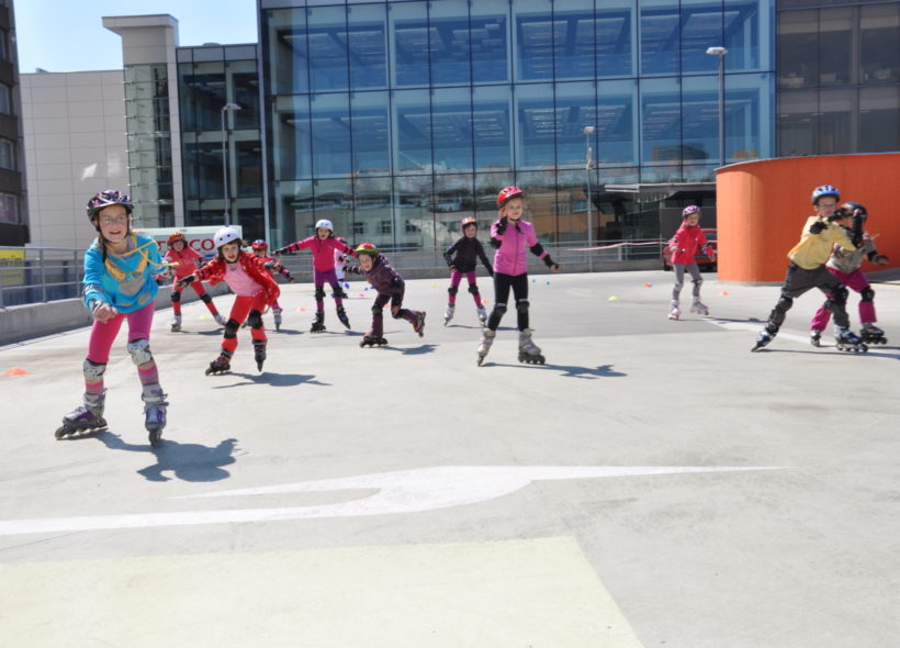 Děti se učí jezdit na bruslích na střeše parkovacího domu.