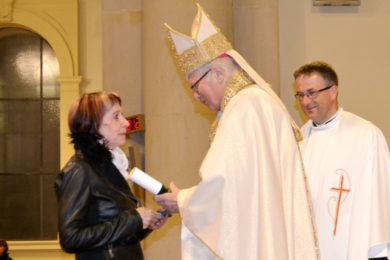 Biskup předává Ludmile Moniakové medaili sv. Hedviky a pamětní list.
