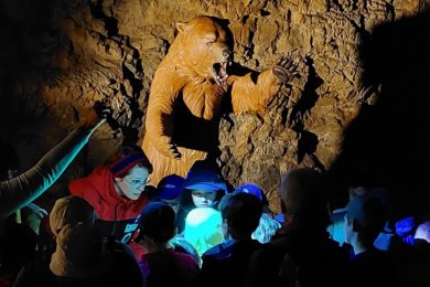 Medvěd Bruno provede děti jeskyní Výpustek v Moravském krasu.  