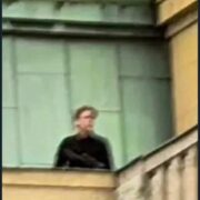 Střelec David Kozák na střeše vysoké školy při střelbě. 