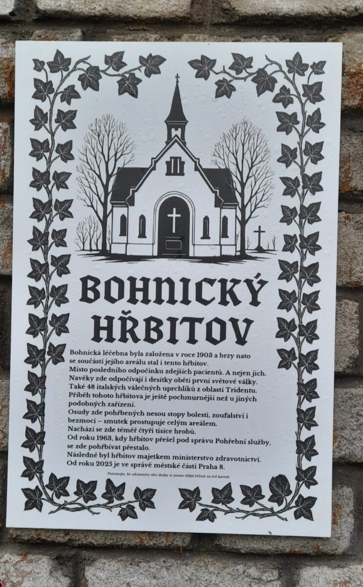 Informační deska na bohnickém hřbitově připomíná jeho pohnutou historii – od založení v roce 1909 přes tisíce pochovaných pacientů a válečných uprchlíků až po období chátrání. Text na ceduli zdůrazňuje, že areál není senzací, ale místem paměti, kde se bolest i úcta prolínají v každém kroku.