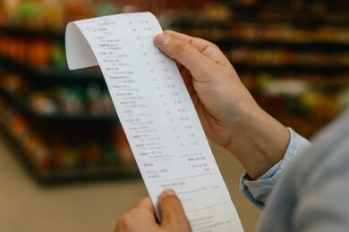 Zákazník kontroluje účtenku – ale skutečná cena potravin zůstává skrytá.  
V českých supermarketech se slevy staly marketingovým trikem, marže řetězců mizí v účetní mlze a výrobci bojují o přežití. Tato fotka zachycuje každodenní moment, který skrývá systémový problém: ceny potravin nejsou náhoda.