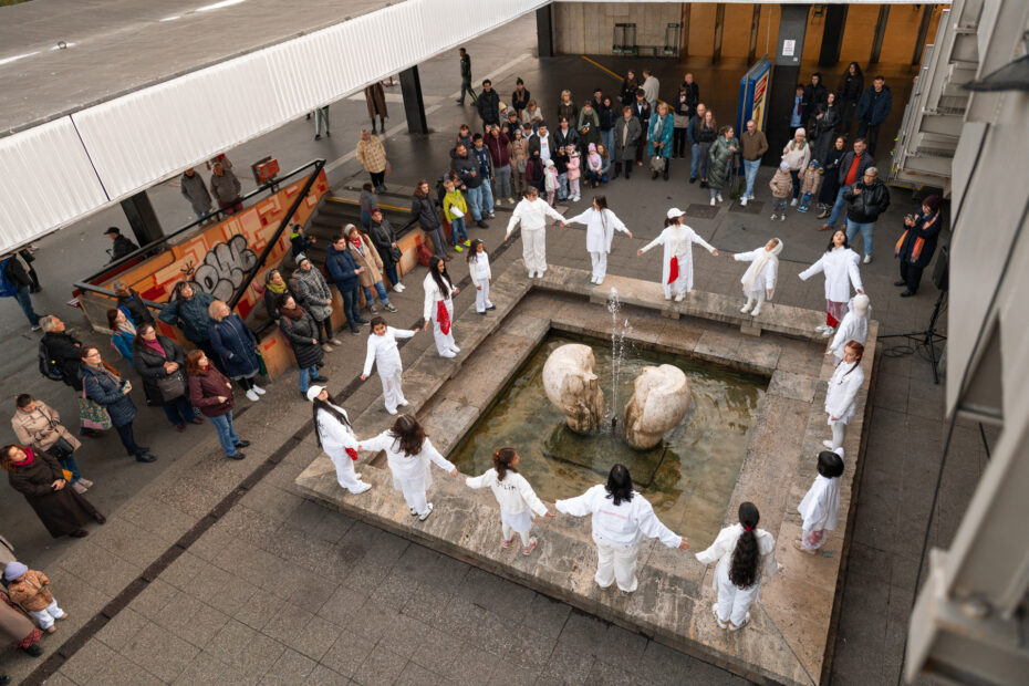 Moment z performativního happeningu KRÁLOVNIČKY, při němž dívky vytvořily rituální kruh kolem kašny v městském prostoru. Akce, která v roce 2024 oživila tradici „otevírání studánek“, se nyní vrací v galerijní podobě v Kobce 17.