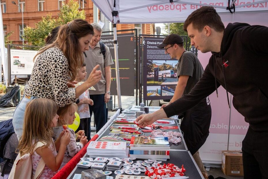 Návštěvníci u informačního stánku PID, kde si mohou vyzvednout drobné dárky a získat aktuální informace o veřejné dopravě v rámci oslav Světového dne veřejné dopravy.