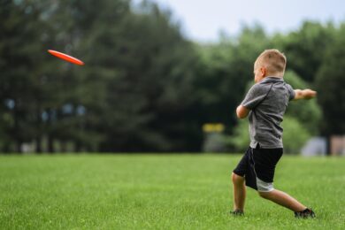 Dítě při hře s frisbee — přesně ten typ volného pohybu, který chytré skříňky LOX v Praze 8 podporují.