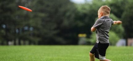 Dítě při hře s frisbee — přesně ten typ volného pohybu, který chytré skříňky LOX v Praze 8 podporují.