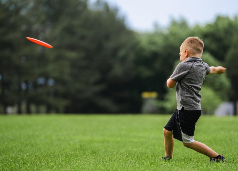 Dítě při hře s frisbee — přesně ten typ volného pohybu, který chytré skříňky LOX v Praze 8 podporují.